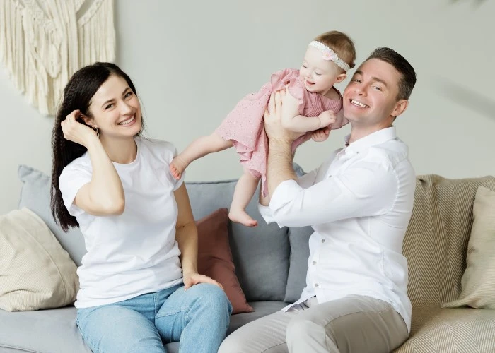 Parents sitting on a sofa playing with their baby